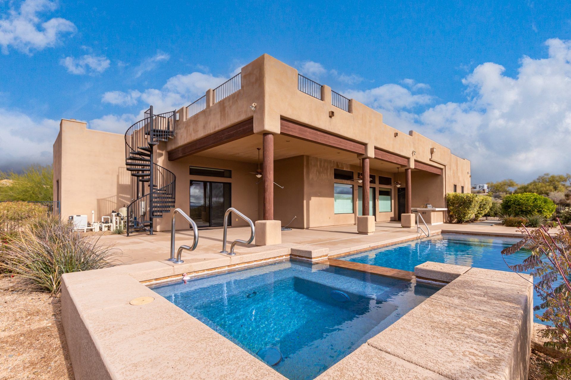 Backyard pool and covered patio with desert views