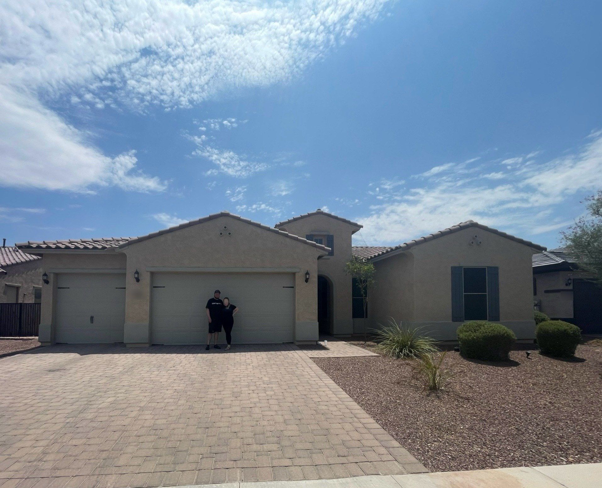 Two happy buyers standing in the driveway of their new single-story home