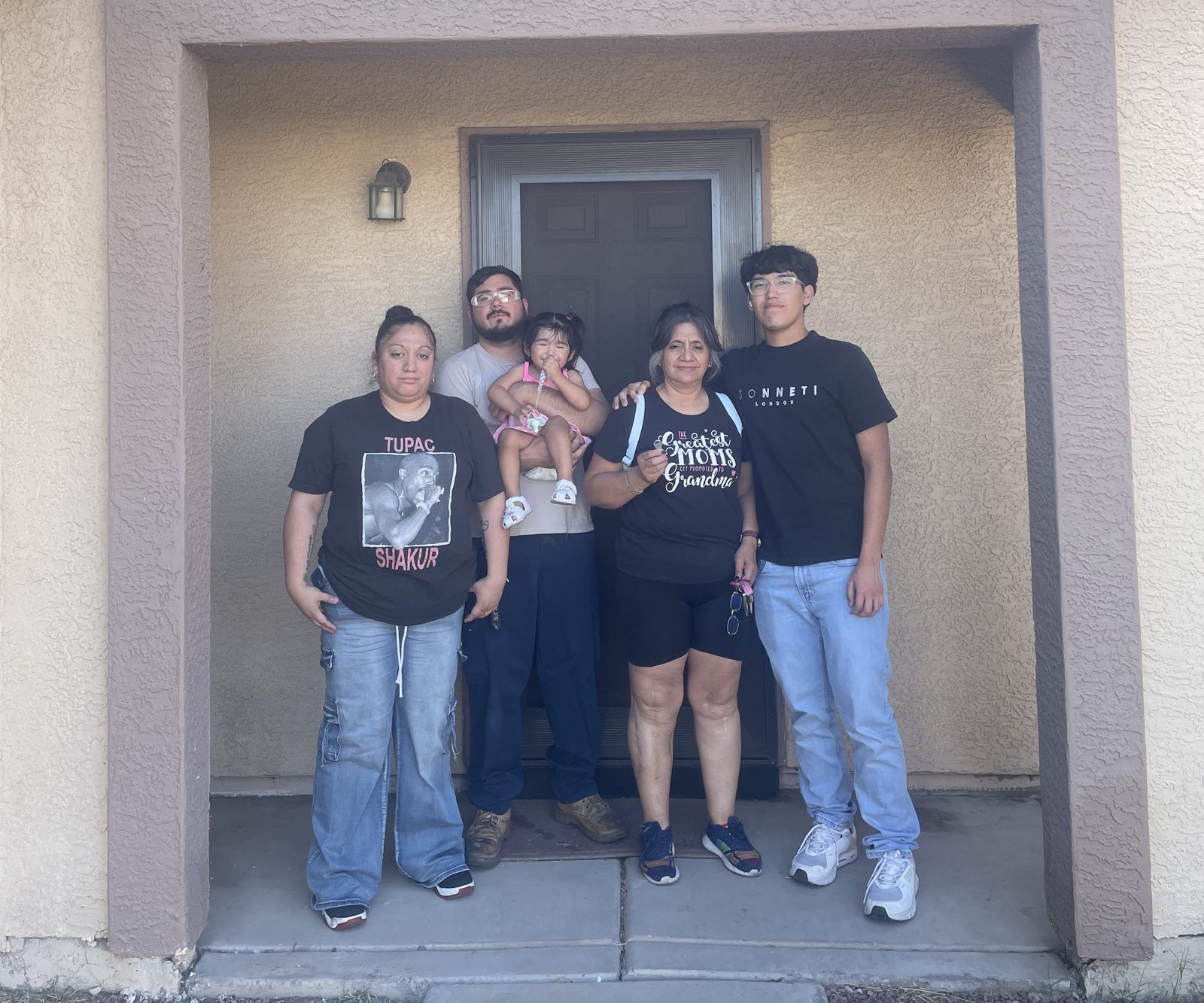 A family standing at the front door of their new home